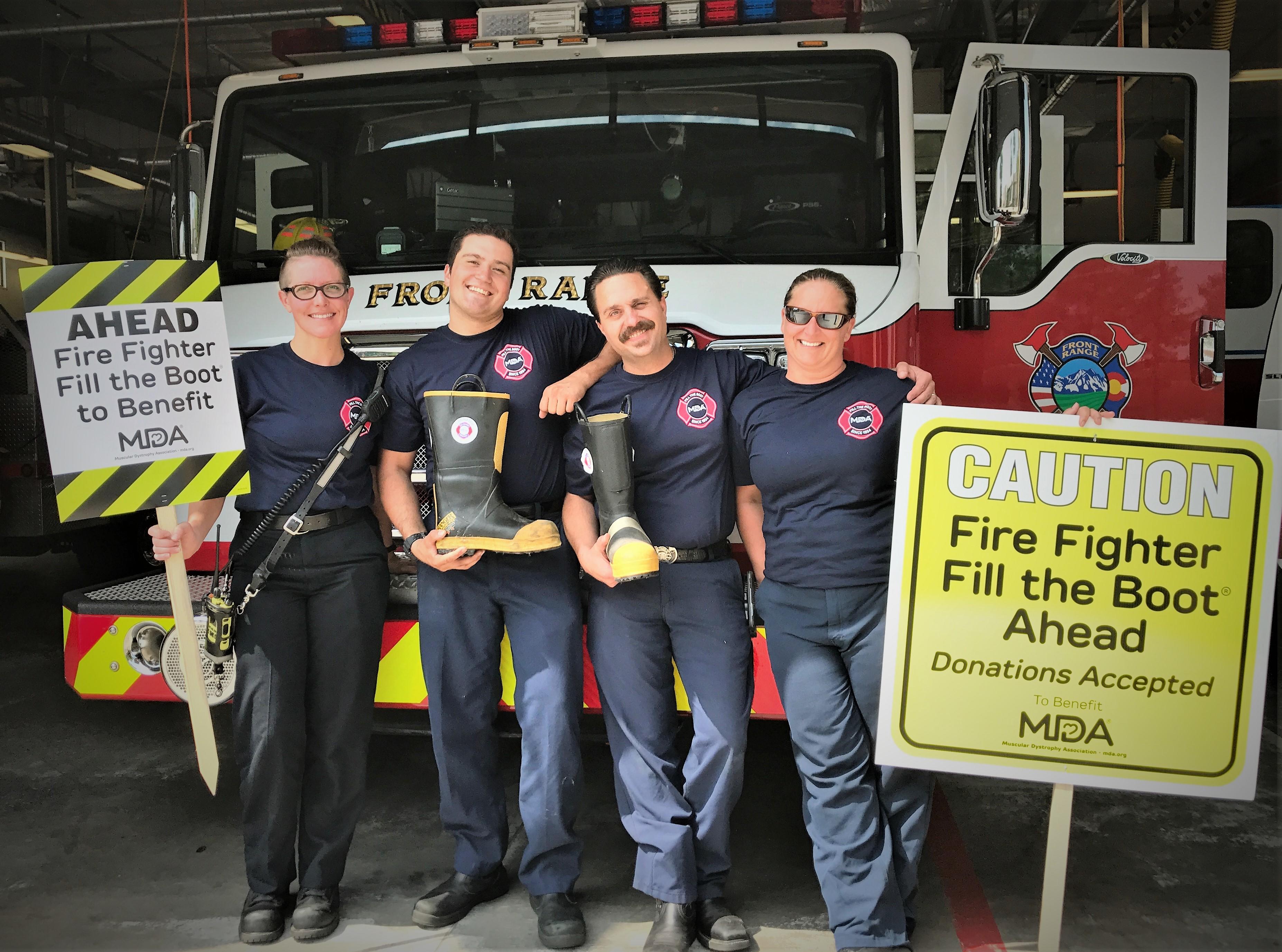 Firefighters standing in front of a firetruck holding boots